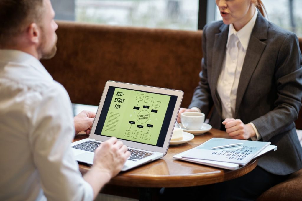 Crafting Captivating Headlines: Your awesome post title goes here A man and woman engaged in a business meeting discussing SEO strategy in a cozy cafe setting.